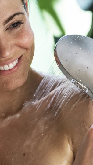 Frau duscht mit einer Handbrause.
