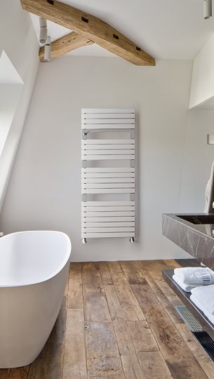 Badheizkörper in einem Badezimmer neben einem Badmöbel und einer Badewanne.