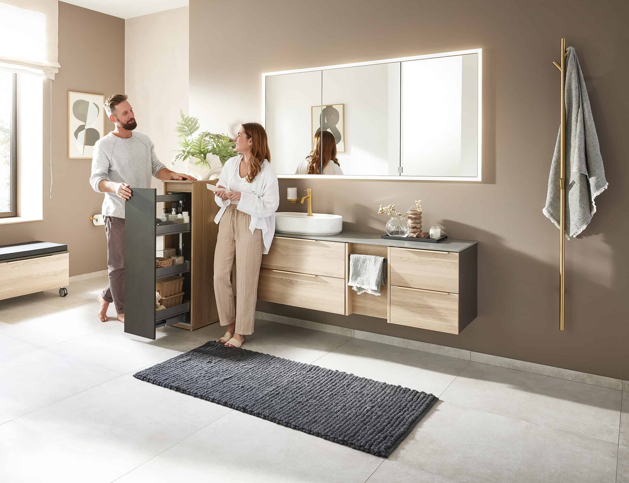 Pärchen freut sich über das neue Badezimmer von Tenne Bad & Fliesen und probiert das Badmöbel aus.